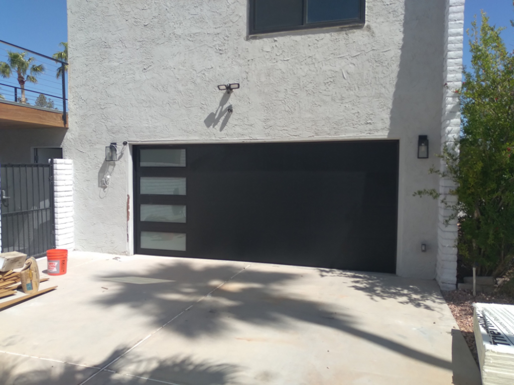 A modern black garage door with frosted glass panels installed by Cactus Garage Doors, Inc. in North Las Vegas, NV.