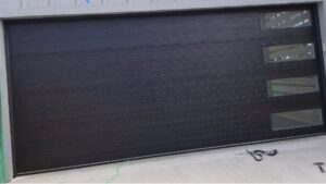 A sleek modern black garage door with horizontal panels and windows by Action Garage Door in Jacksonville, AR.