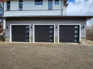 Three modern black garage doors with frosted windows installed by Compton Doors, Inc. in Attleboro, MA