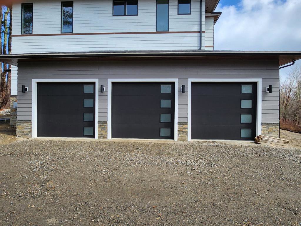 Three modern black garage doors with frosted windows installed by Compton Doors, Inc. in Attleboro, MA