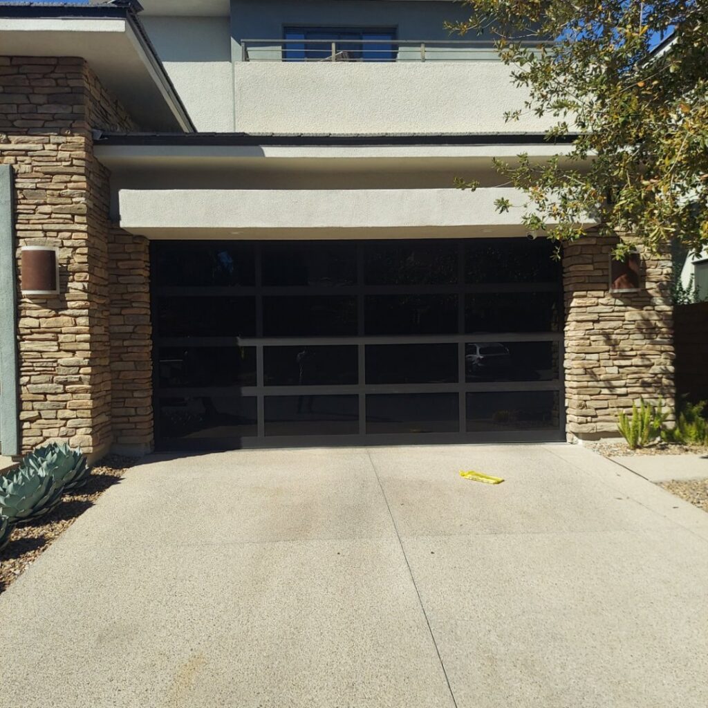 A modern black glass garage door installed by Giddy Up Garage Doors & Iron in Las Vegas, NV.