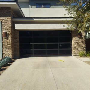 A modern black glass garage door installed by Giddy Up Garage Doors & Iron in Las Vegas, NV.