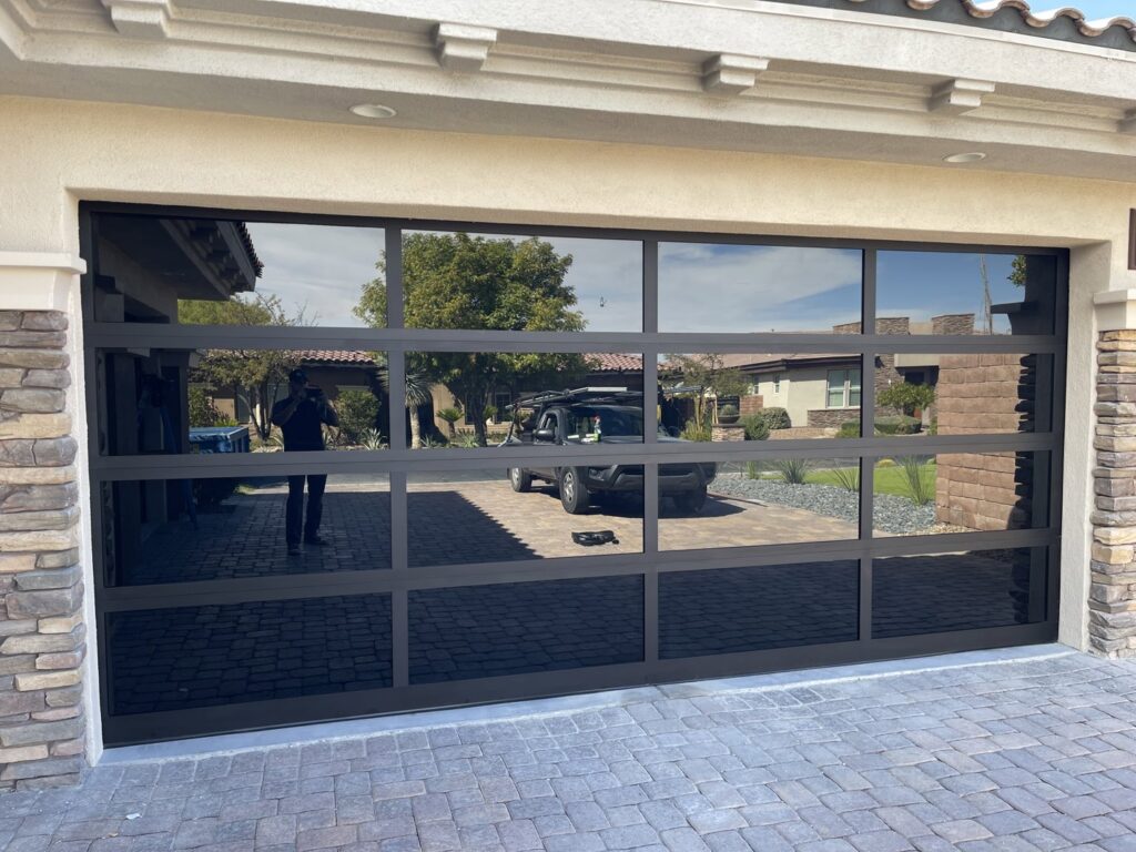 A sleek modern black glass garage door installed on a home by Legacy ODS Garage Door Services in Las Vegas, NV.