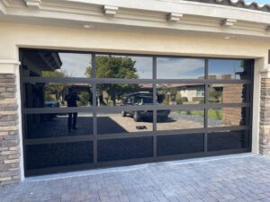 A sleek modern black glass garage door installed on a home by Legacy ODS Garage Door Services in Las Vegas, NV.