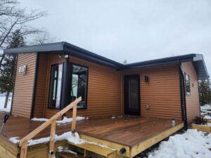 A modern cabin-style house with brown horizontal siding, a completed project by Murphy Builders- Genesee County in Ossineke, MI.