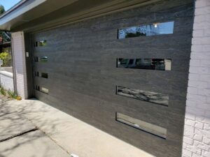 A modern dark gray garage door with horizontal windows installed on a residential home by Precision Garage Door of Albuquerque and Santa Fe, NM.