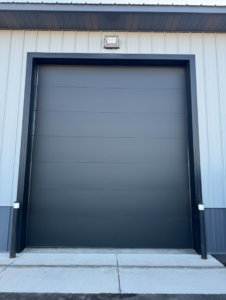 A modern dark grey garage door installed on a commercial building by Steelhead Doors, Services Available In.