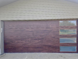 A modern dark wood finish garage door with horizontal windows installed by Champion Overhead Door in Brattleboro, VT.