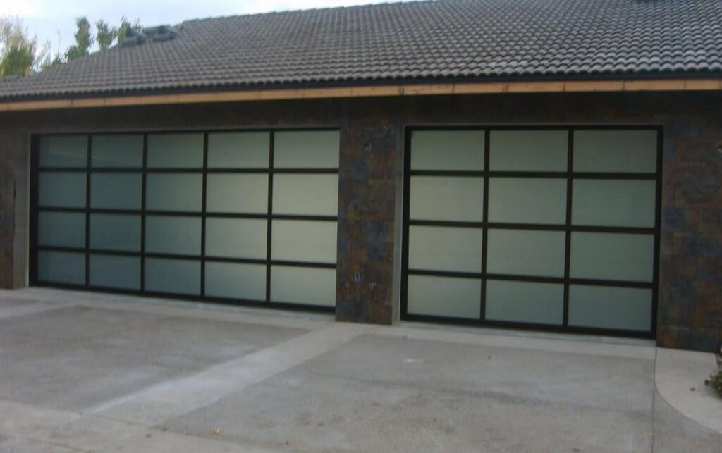 Two modern garage doors with frosted glass panels and dark frames installed on a home by Wahlen Garage Doors in Ogden, UT