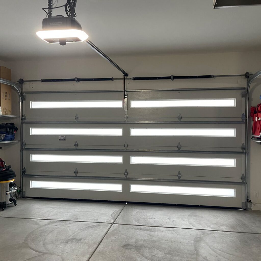 An interior view of a modern garage door with horizontal windows and an overhead garage door opener, installed by American Veteran Garage Door Repair Henderson, NV.