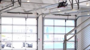 Modern glass garage doors with visible operating mechanisms inside a building by Vertical Door Solutions in Sheridan, WY