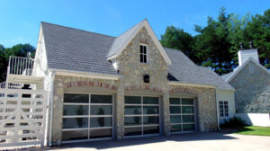 Two modern glass garage doors with white frames installed on a stone house by Coney's Garage Doors in Conway, AR.