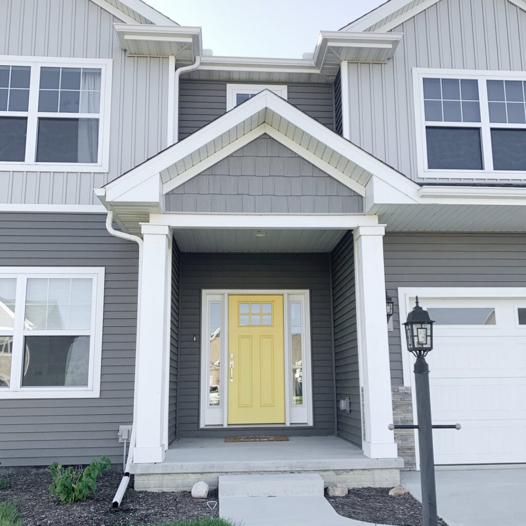 A modern home with gray horizontal and shake siding and a bright yellow door by Bushco Contracting LLC in Fresno, CA.