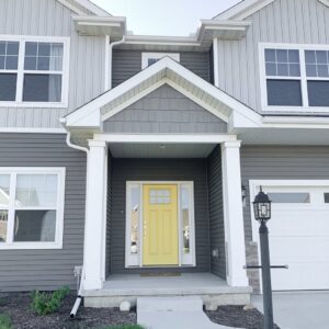 A modern home with gray horizontal and shake siding and a bright yellow door by Bushco Contracting LLC in Fresno, CA.