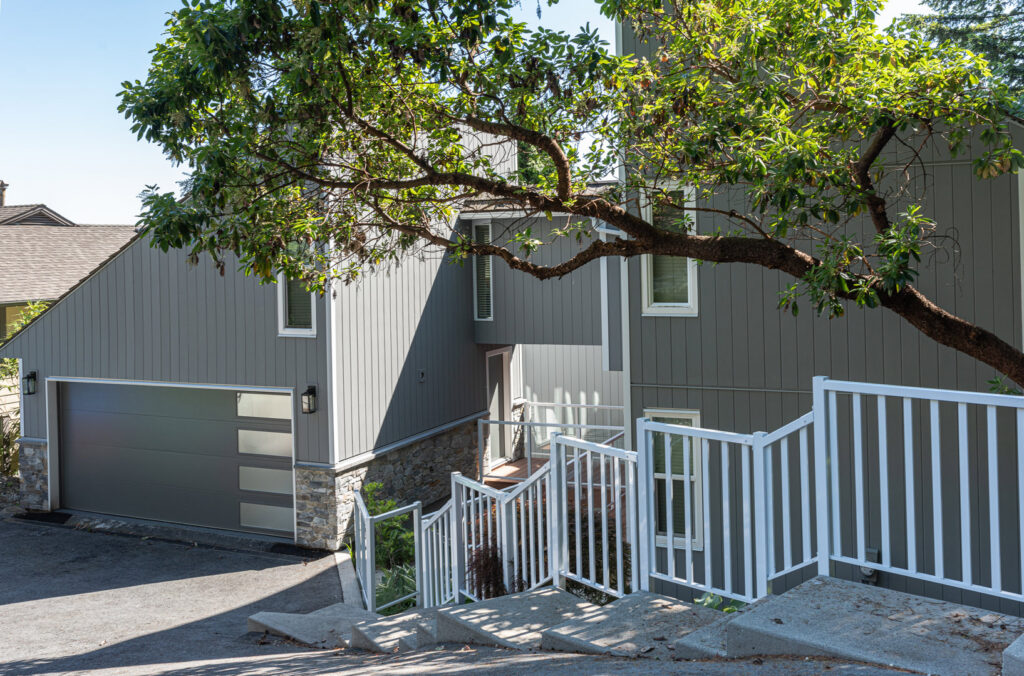A modern home featuring gray siding and stone accents installed by Ideal Siding Dallas, TX.