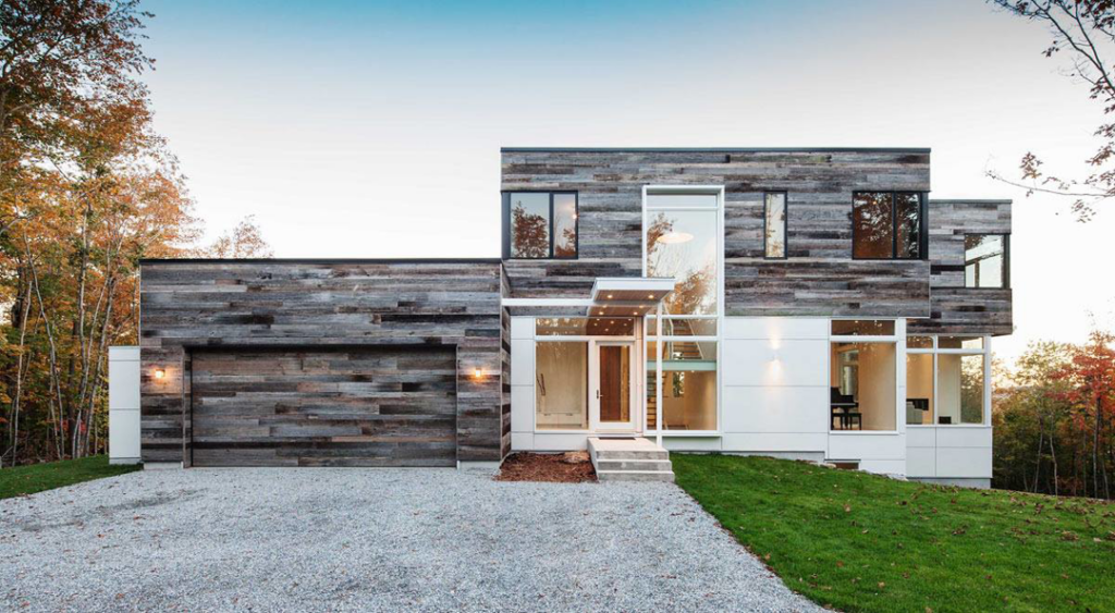 A modern home showcasing a combination of wood-look and white panel siding by CityWide Roofing Rochester in Webster, NY.
