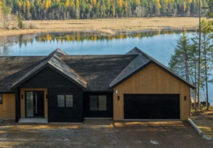 A modern house featuring a sleek black garage door, installed by Steelhead Doors, Services Available In.