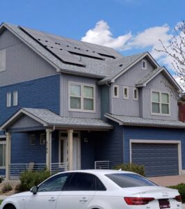 A modern house with blue vertical and horizontal siding and solar panels, installed by Urban Exteriors LLC in Lakewood, CO.