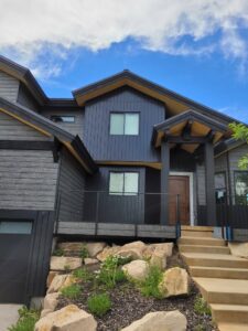 A modern house featuring dark gray vertical siding and natural wood accents, a project by New Look Siding in Midvale, UT.
