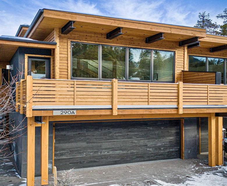 A modern house featuring a dark horizontal panel garage door installed on the lower level by Bailey Garage Doors MT in Belgrade, MT.
