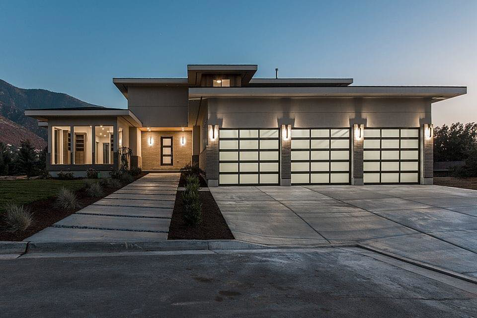 A modern house featuring two stylish glass panel garage doors installed by Windsor Door Sales Inc. in Ogden, UT.