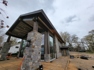 A modern house exterior under construction with stone and wood siding by PMC Company in Brooklyn Park, MN.