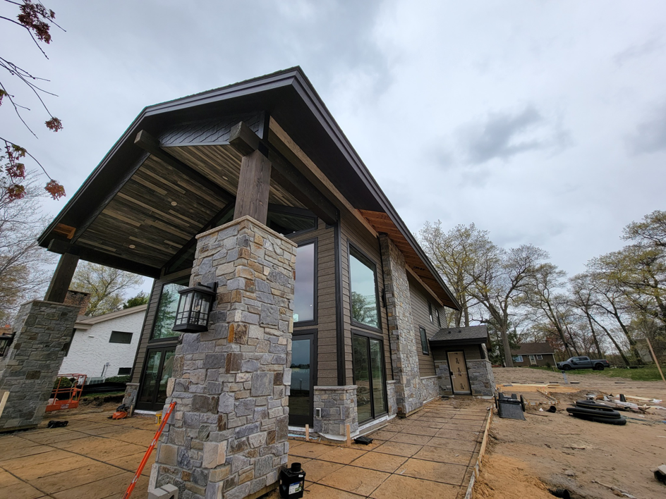 A modern house exterior under construction with stone and wood siding by PMC Company in Brooklyn Park, MN.