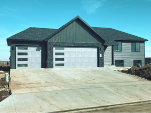 A modern house featuring two newly installed garage doors, showcasing the quality work of American Garage Door Minot in Minot, ND.