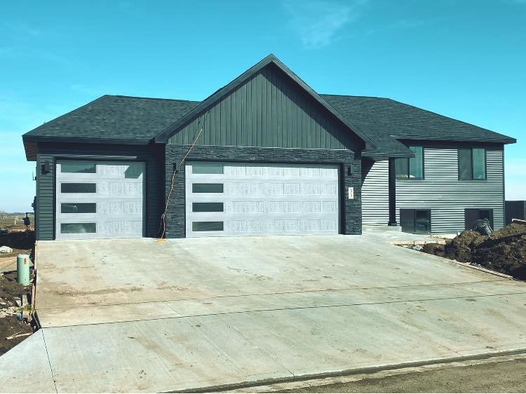A modern house featuring two newly installed garage doors, showcasing the quality work of American Garage Door Minot in Minot, ND.