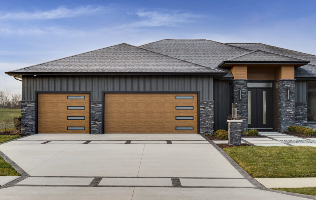 A modern house featuring two wooden-look garage doors with horizontal windows by Pioneer Overhead Door, Inc in Las Vegas, NV.
