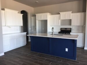 A modern kitchen with white cabinets and a blue island, impeccably cleaned by Pristine Cleaning Concepts in Stillwater, OK.