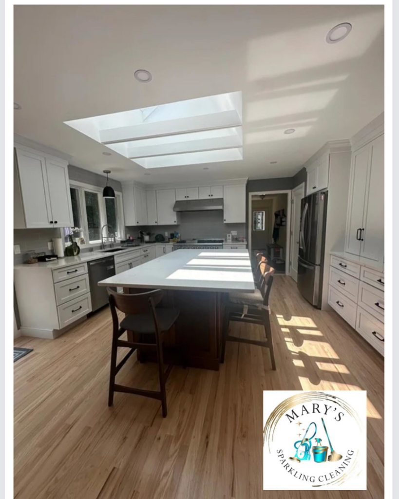 A modern kitchen with white cabinets and a large island, looking spotless after a professional cleaning by Mary's Sparkling Cleaning in Fall River, MA.