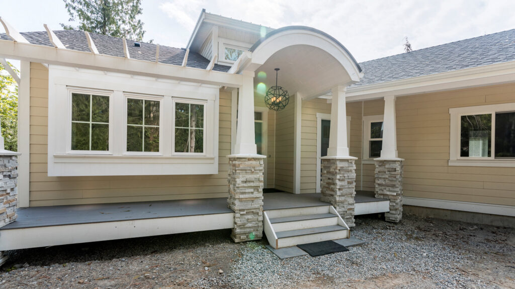 A modern house featuring light beige horizontal siding and stone pillars by Ideal Siding Winston-Salem, NC.