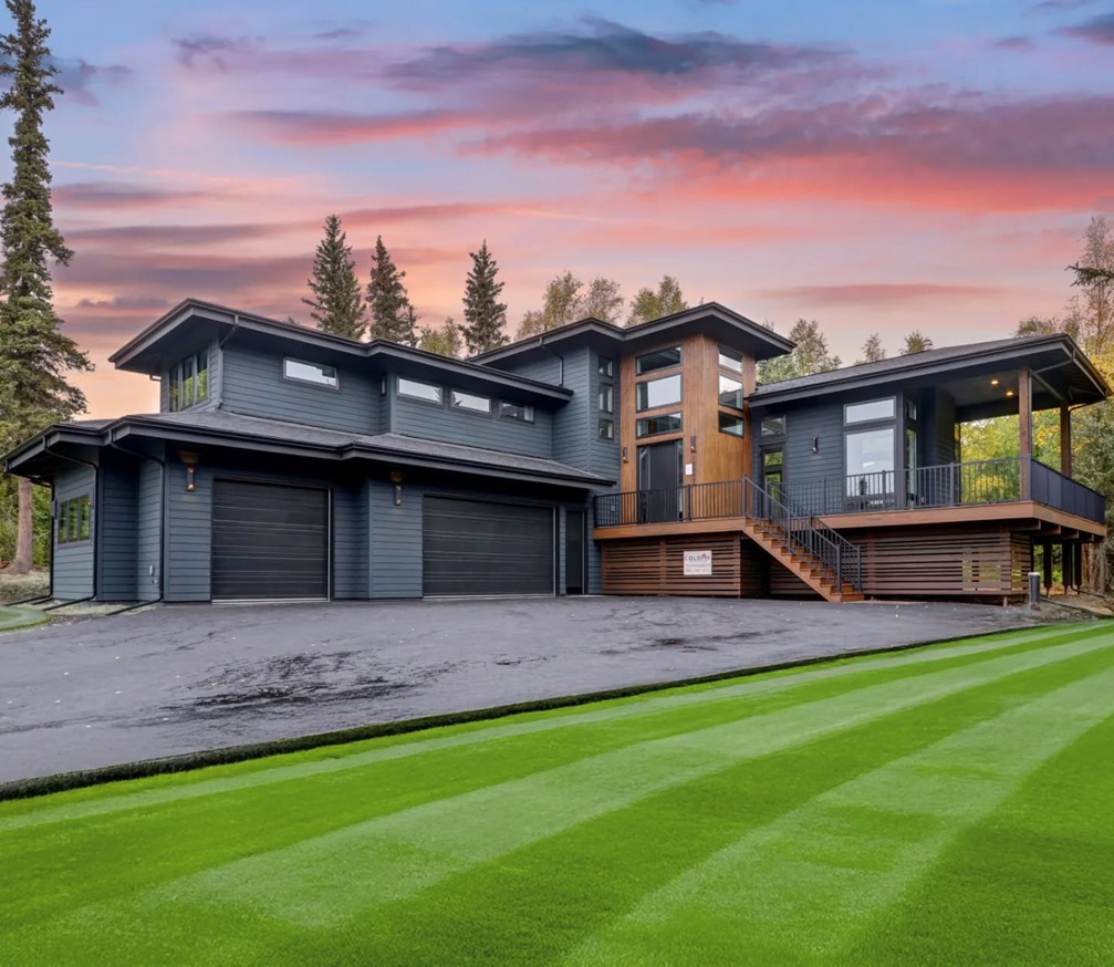 Modern residential garage doors installed on a house by Alaska Door in Wasilla, AK, at sunset.