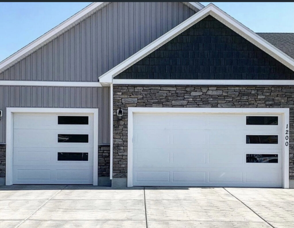 A residential home featuring two modern white garage doors with horizontal windows by Overhead Door Company of Little Rock in North Little Rock, AR.