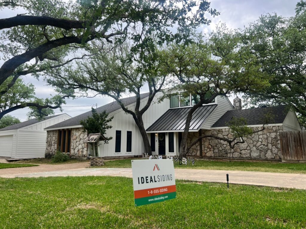 A modern home with white vertical siding and stone accents, showcasing a completed project by Ideal Siding Austin in Austin, TX.