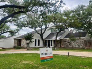 A modern home with white vertical siding and stone accents, showcasing a completed project by Ideal Siding Austin in Austin, TX.