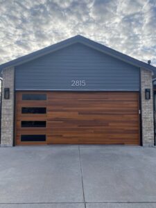 A modern wood-look garage door with horizontal windows installed on a house by Apex Garage Doors in Columbus, OH.
