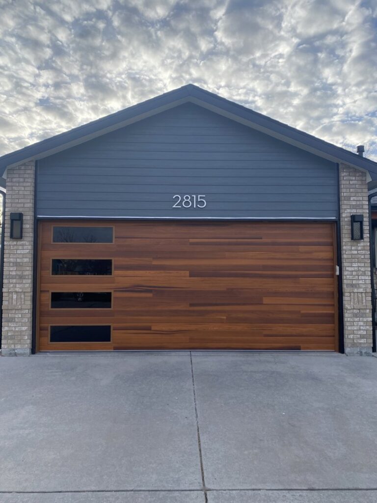 A modern wood-look garage door with horizontal windows installed on a house by Apex Garage Doors in Columbus, OH.