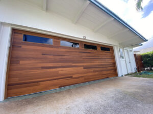 A newly installed modern wood-look garage door with windows by Oahu Garage Doors in Waipahu, HI