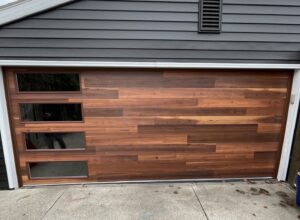 A modern wood-look garage door with horizontal windows installed by PS GARAGE DOORS in Grand Forks, ND