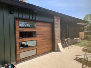 Modern wood-look garage door with three frosted windows installed on a house by Garage Door Store Boise, ID.