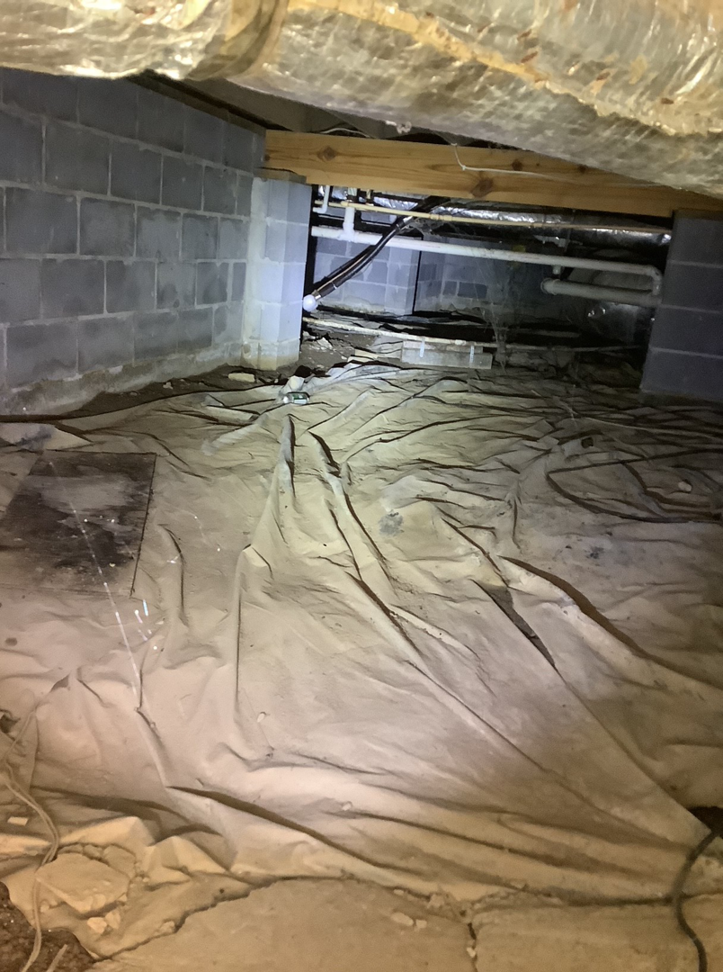 A crawlspace with a dirty, moisture-damaged vapor barrier, indicating water issues for Allied Foundation & Crawlspace Solutions in Decatur, AL.