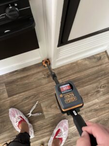 A water damage specialist using a moisture meter to detect hidden water in a hardwood floor, by Elements of Restoration in Denver, CO.