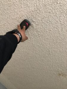 A technician using a moisture meter to inspect a ceiling for hidden water damage at Anytime Flood Restoration in Thornton, CO