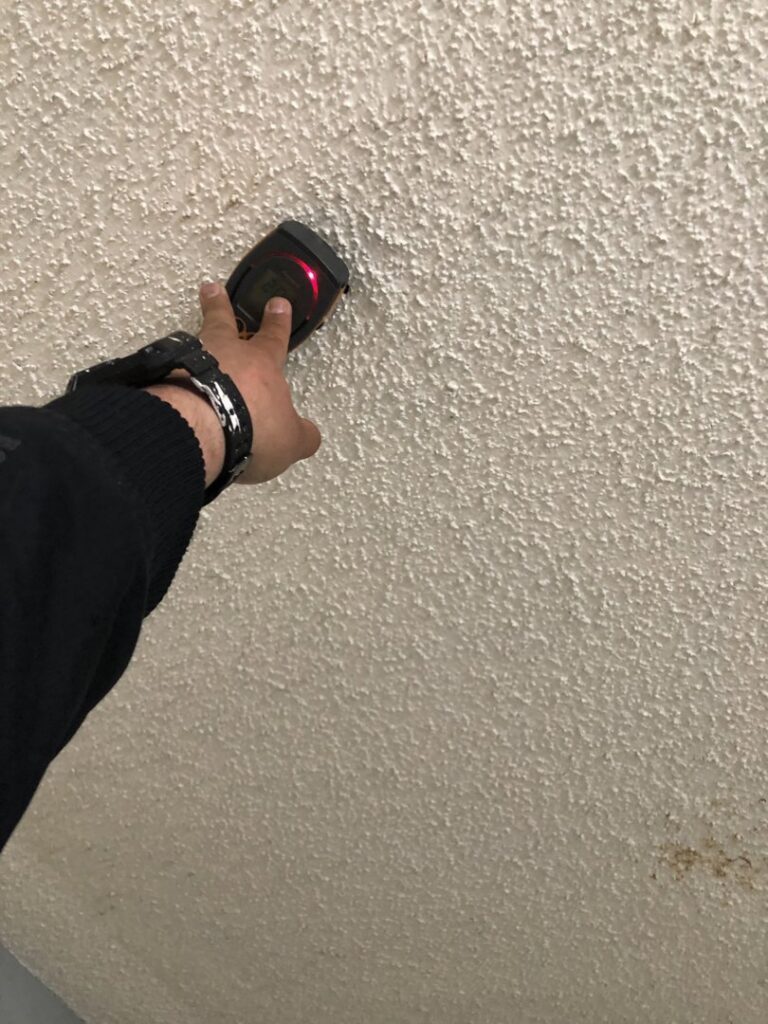 A technician using a moisture meter to inspect a ceiling for hidden water damage at Anytime Flood Restoration in Thornton, CO