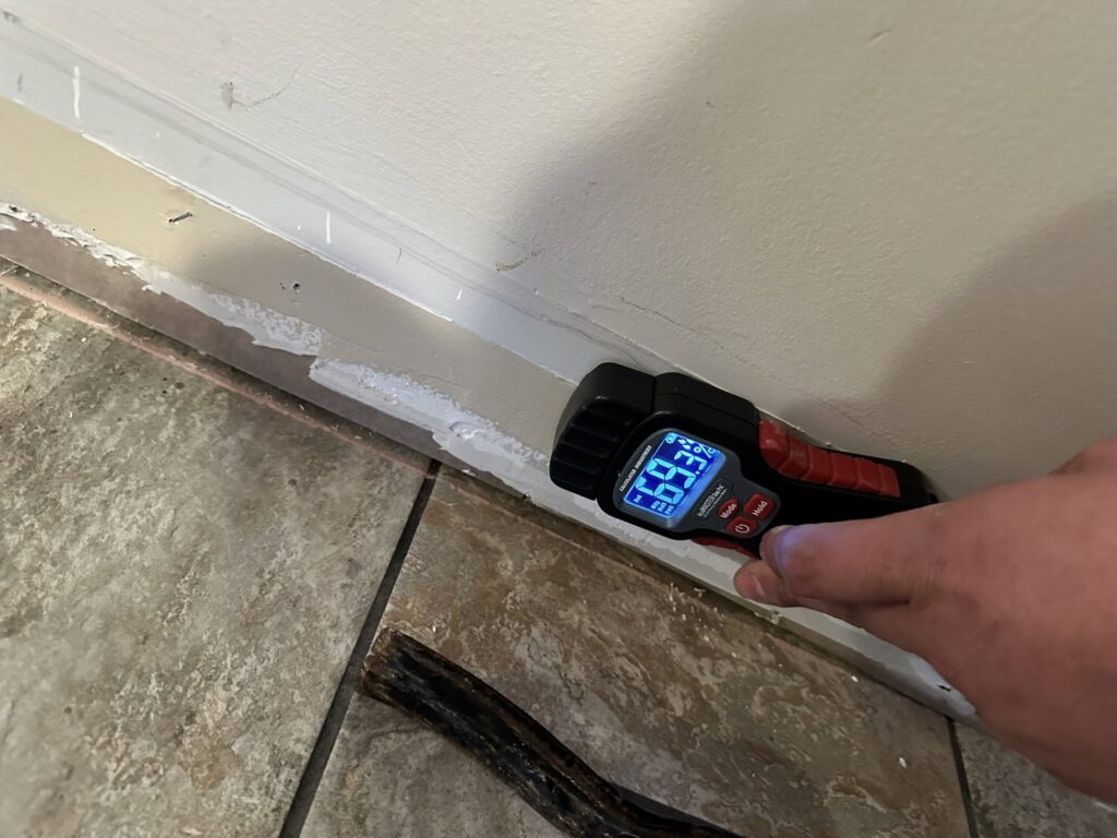 A moisture meter checking the dampness of a wall during water damage assessment by Restoration Alliance Services in Elk River, MN.