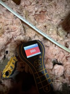 A moisture meter detecting high moisture in insulation during water damage assessment by Restoration Xperts Emergency 24/7 in Deerfield Beach, FL.
