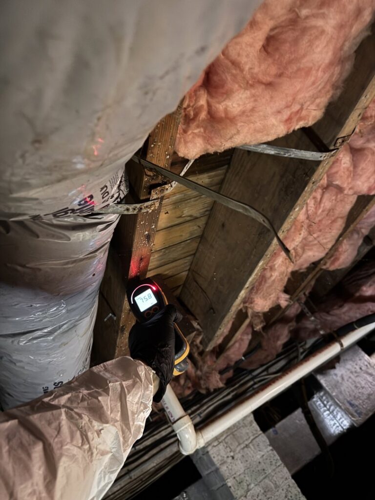 A moisture meter inspecting damp ceiling insulation and wood beams for water damage by Island Emergency Disaster Restoration in Farmingdale, NY.