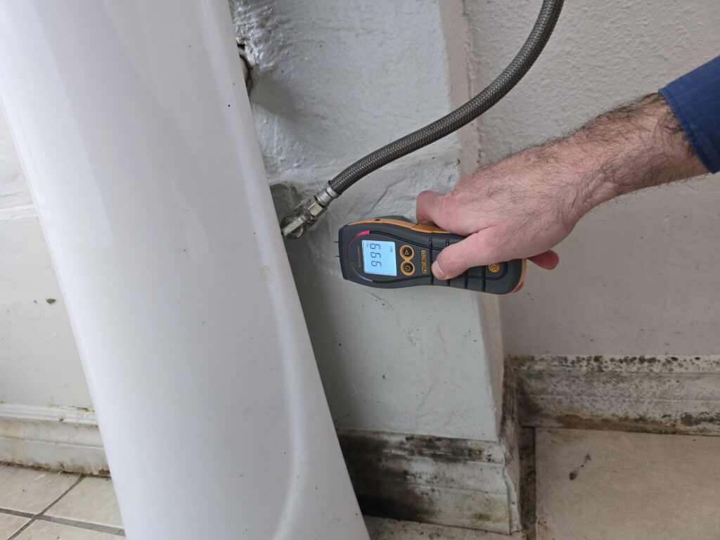 A technician performing a moisture meter inspection for water damage near a toilet at Risk Free Serv Water Damage Repair San Diego, CA